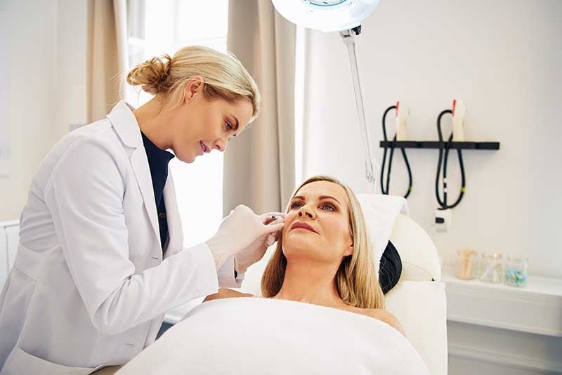 Une professionnelle en soins esthétique de la clinique Belladerma Dix30 située à Brossard, effectuant une injection d'acide hyaluronique sur une patiente